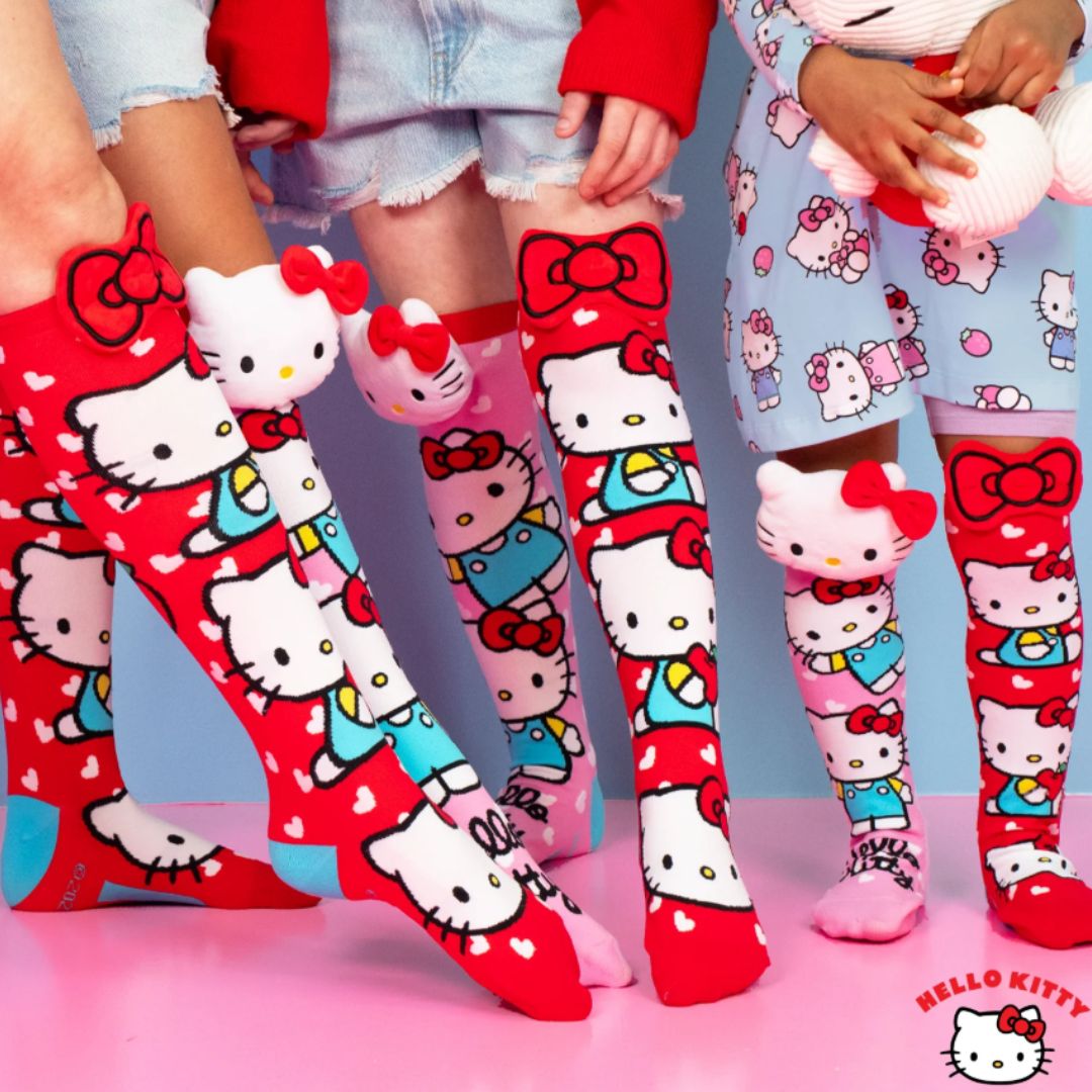 Chaussettes hautes Hello Kitty MADMIA dépareillées pour enfants, avec éléments en peluche 3D, une rose avec tête Hello Kitty, l’autre rouge avec pomme et nœud.